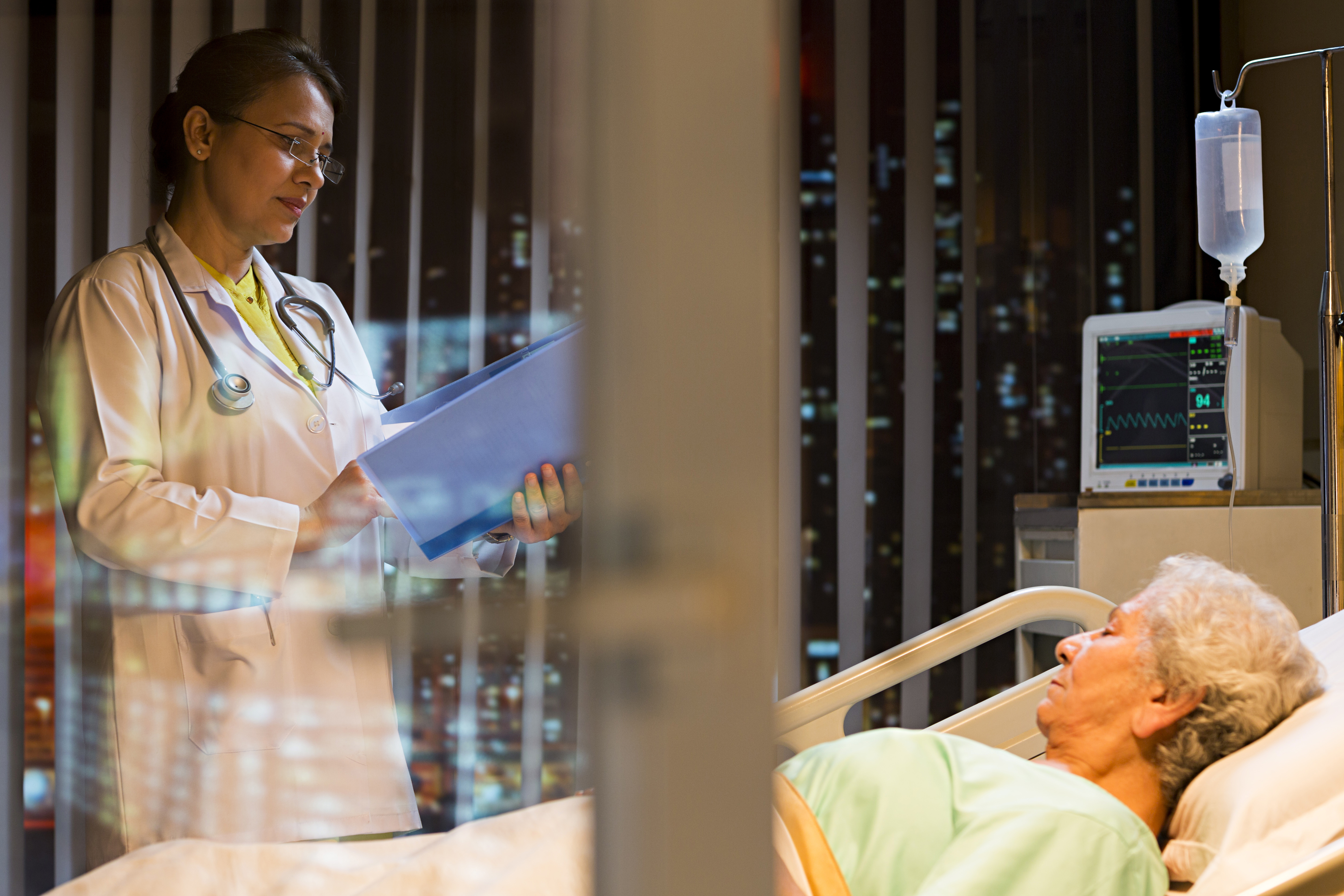 Woman patient lying on bed and doctor examining file