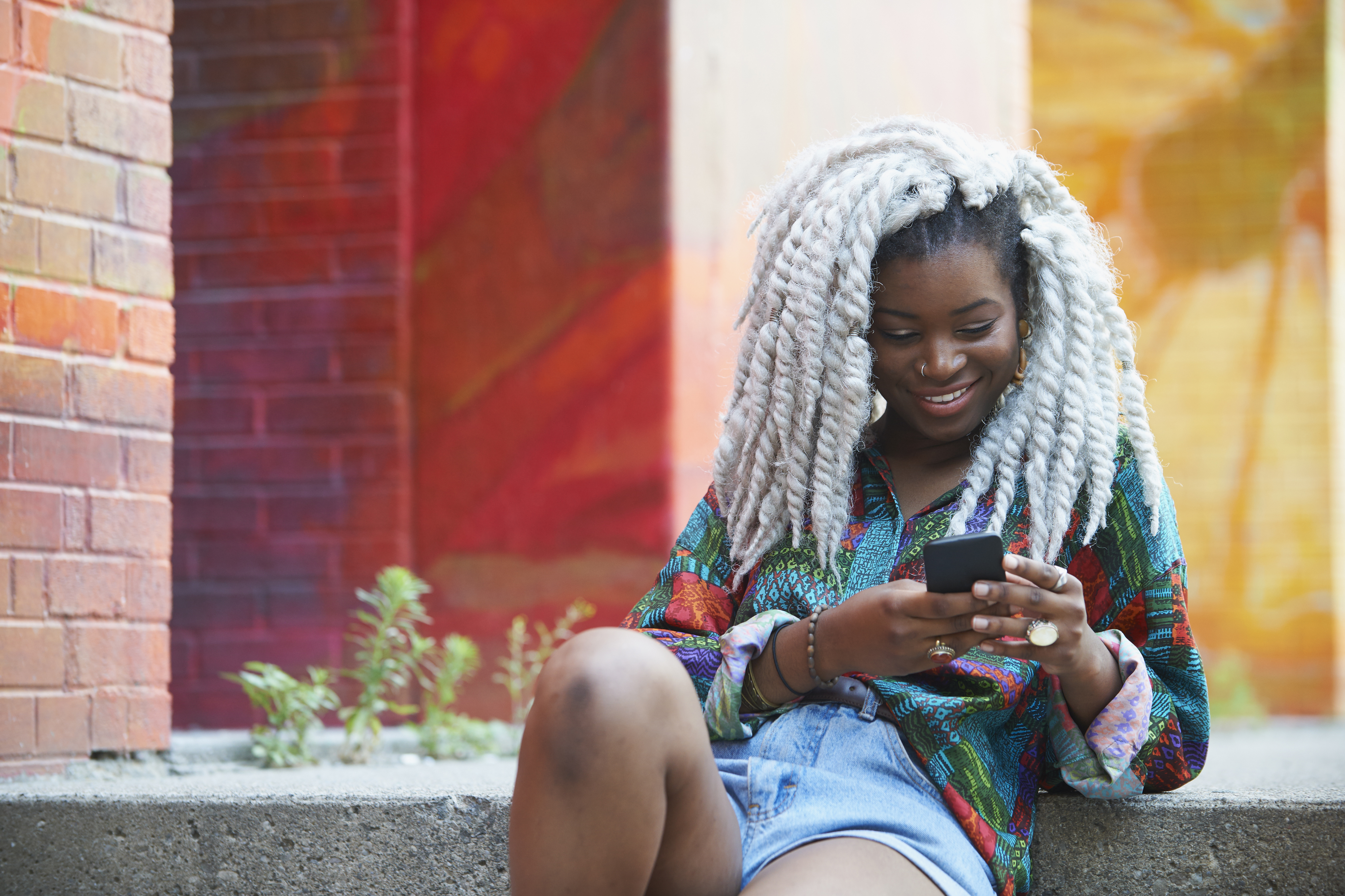 Smiling Black woman texting on cell phone