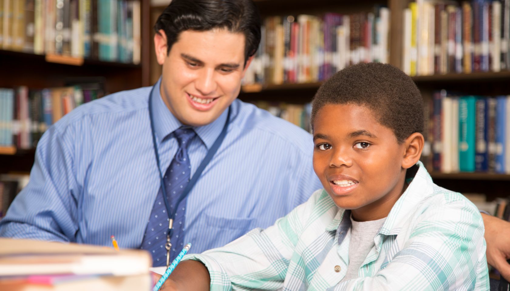 Teacher, mentor helps elementary-age schoolboy with homework.