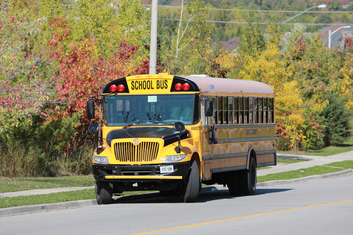 Yellow school bus on autumn background