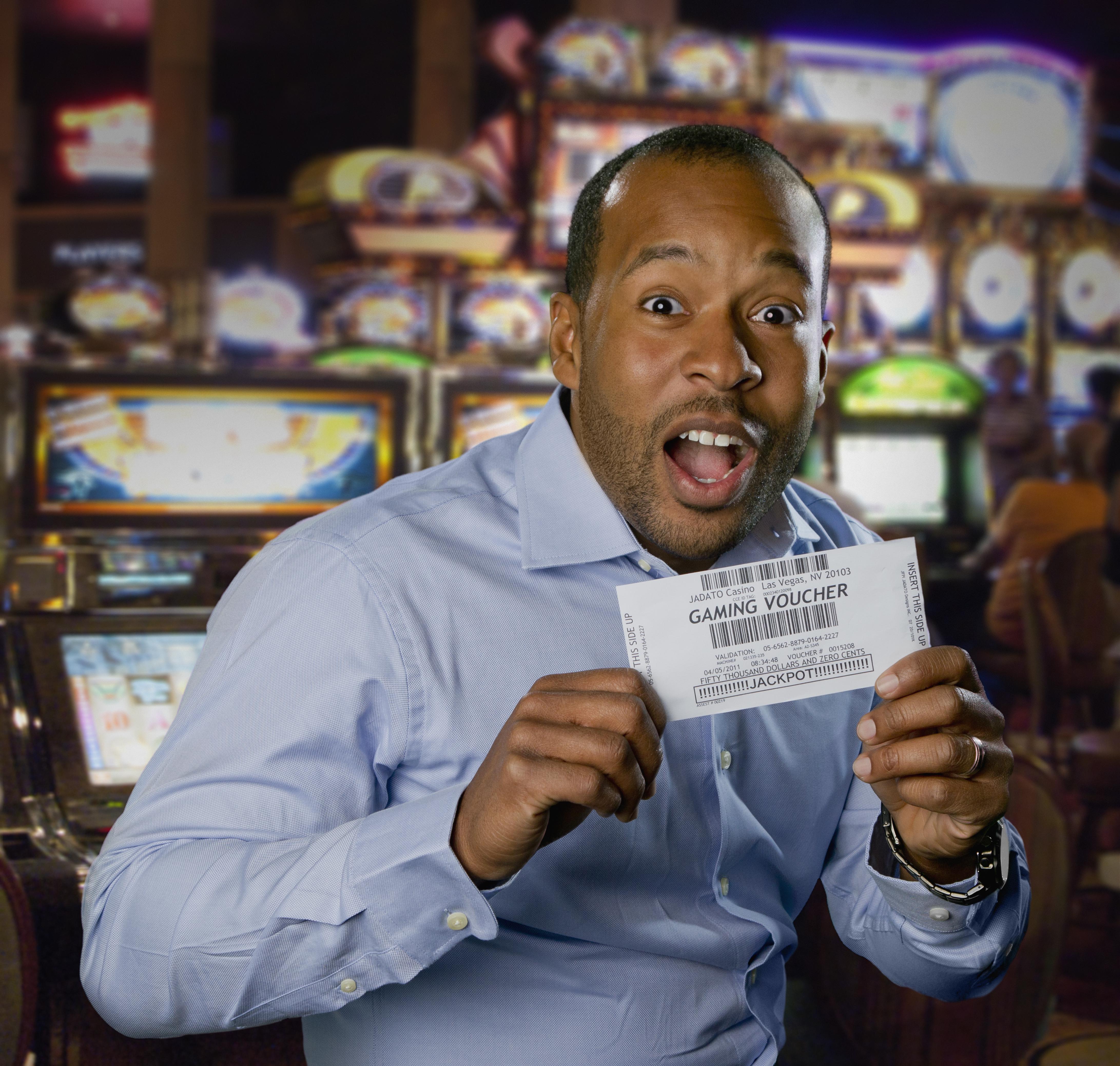 Excited African American man holding gaming voucher in casino