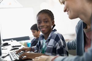 Portrait smiling pre-adolescent girl at computer in classroom